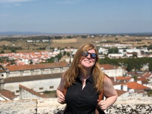 Sarah smiling, against the backdrop of a landscape in Portugal